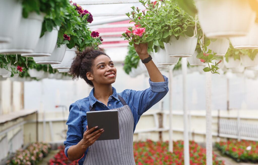 Innovation technology for smart farm system. Girl checks flowers in greenhouse with tablet in her